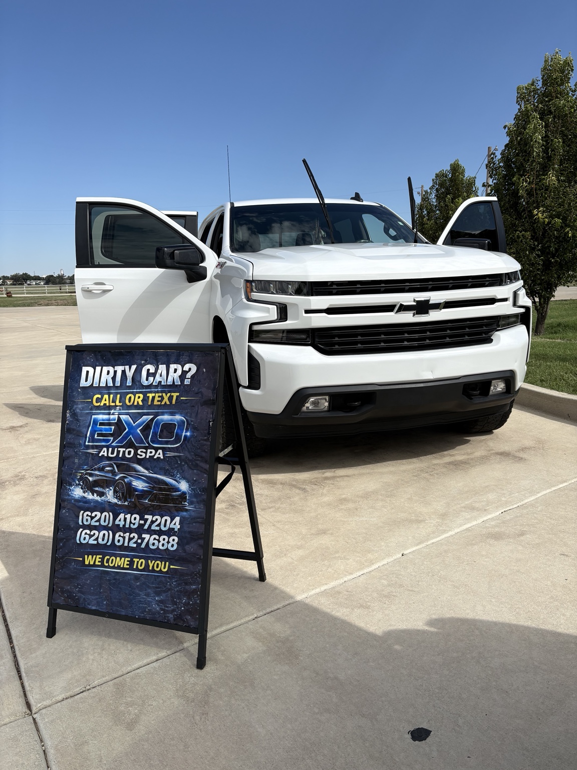 Clean white Chevrolet Silverado displayed beside an EXO Auto Spa sign